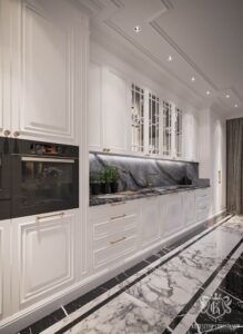 آشپزخانهای با طراحی نئوکلاسیک و بین کابینتی سنگی تیره با رگههای سفید و طوسی، ترکیب شده با کابینتهای سفید و دستگیرههای طلایی، نمایی لوکس و مدرن ایجاد کرده است.